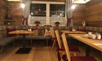 A cozy restaurant with wooden decor and Christmas accents. Tables are set, and an inviting atmosphere prevails.