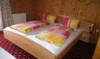 A cozy bedroom with a double bed and colorful duvets. Wooden paneling on the walls and a warm carpet create an inviting atmosphere.