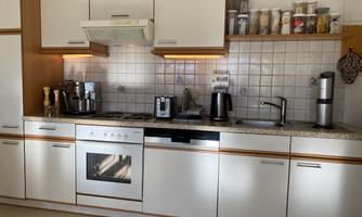 A modern kitchen with bright cabinets and a stylish granite countertop. Various kitchen appliances and utensils are on the countertop.