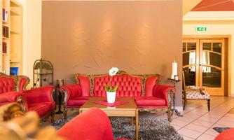 An elegant living room with red upholstered sofas and a table in the middle. A plant in a white pot adds a fresh accent.