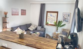 A modern living room with a cozy couch and a large window front. The room is tastefully decorated and offers an open view of the surroundings.