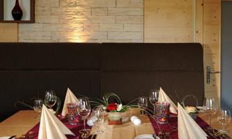 An elegantly set table in a cozy restaurant. The decoration includes folded napkins, glasses, and a beautiful table flower.