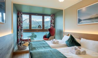 A comfortable room with two beds and a view of a picturesque landscape. Large windows let in plenty of daylight and create an inviting atmosphere.