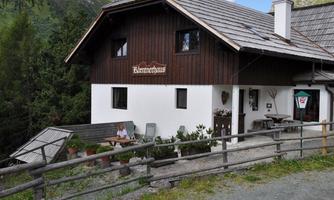 A traditional wooden house in the mountains with an inviting outdoor area. Surrounded by trees and green nature.