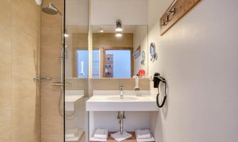A modern bathroom with a clear shower and an elegant sink. Soft colors and plenty of light create an inviting atmosphere.
