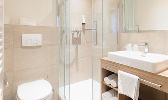 A modern bathroom with a glass shower and a wooden vanity. The walls are painted in neutral colors and provide a clean, bright atmosphere.