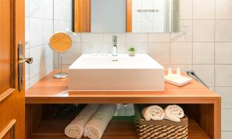 A modern bathroom with a stylish sink and wooden shelves. Towels and toiletries are neatly arranged.