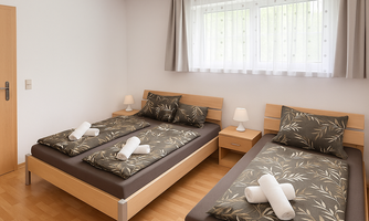 A simple and clean bedroom with two single beds. The decorated beds are equipped with towels and there are windows with curtains.