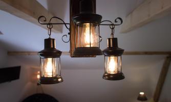 A stylish ceiling lamp with three hanging lanterns. The lamps emit warm light in a cozy room.