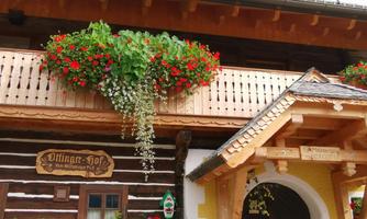 A traditional wooden house with a beautiful balcony decorated with colorful flowers. The facade has a charming rustic appeal.