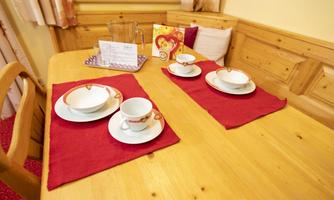 A table set with white cups and plates on red placemats. The atmosphere is cozy and inviting.