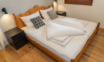 A cozy bedroom with a double bed and two nightstands. The bedding is white and there are decorative pillows on the bed.