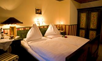A cozy bedroom with a double bed and traditional, pointed pillows. The warm lighting and wooden details create an inviting atmosphere.