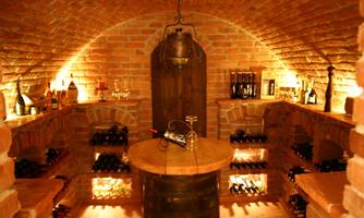 A cozy wine cellar with brick walls and soft lighting.  
Shelves full of wine bottles and a round wooden table in the center.