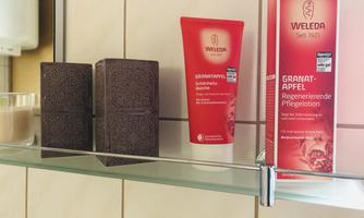 On the shelf, there are care products from Weleda. There is a body cream and a regenerating care product with pomegranate on display.