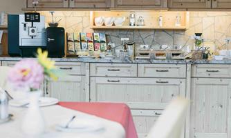 An inviting breakfast nook with a coffee machine and various types of tea. The light wooden bench and decorative details create a warm atmosphere.