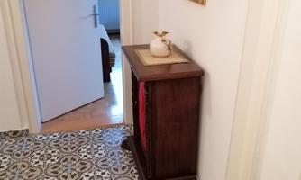 A hallway with an elegant wooden sideboard and a wall lamp. The floor is designed with decorative tiles.