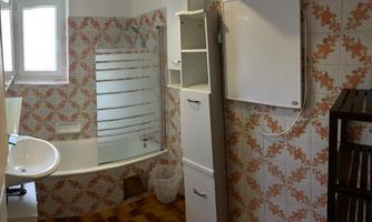 A bathroom with a bathtub, a sink, and modern tiles. The room has a window and bright walls with decorative patterns.