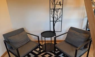 A cozy reading corner with two chairs and a small table. The decor is modern and minimalist, complemented by a stylish rug.