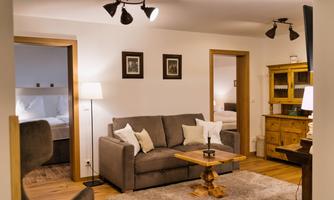 A cozy living room with a gray sofa and wooden furniture. The warm colors and soft lighting create an inviting atmosphere.
