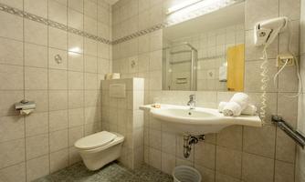 A modern bathroom with bright tiles. It includes a sink, a toilet, and a mirror.