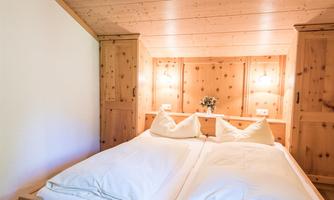 A cozy bedroom with wooden details and two separate beds. Soft lighting creates a relaxed atmosphere.
