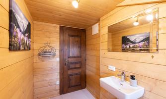 A cozy wooden bathroom with a sink and a large mirror. Pictures of mountain landscapes hang on the wall.