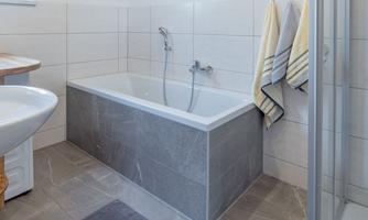A modern bathroom with a bathtub, a sink, and a shower. Towels in soft colors hang on the wall.