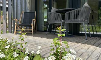 A terrace with modern furniture and blooming plants. The space feels inviting and bright.