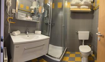 A modern bathroom with a shower, sink, and toilet. The walls are designed in shades of gray, with colorful accents in yellow.