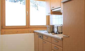 A modern kitchen with wooden cabinets and large windows. The cooking utensils are neatly arranged on the countertop.