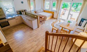 A bright and modern kitchen with a dining area in a cozy room. Large windows provide a view of the outdoors and allow plenty of daylight in.