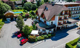 A picturesque hotel with a beautiful facade and a well-maintained outdoor area. The surroundings are green and hilly, ideal for a relaxing stay.