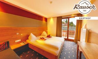 A cozy hotel room with two beds and a balcony. The walls are painted in warm colors, and the room is bright and inviting.