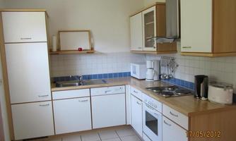 A modern kitchen with white cabinets and wooden surfaces. It is well-equipped with appliances such as an oven, a microwave, and a coffee maker.