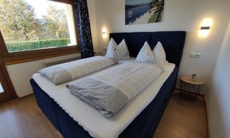 A modern bedroom with a large bed and two pillows. The room has a window that lets in daylight and creates a relaxing atmosphere.