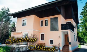 A charming guesthouse with a bright facade and a wooden roof. Surrounded by trees and a clear sky.