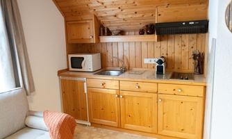A small kitchen with wooden shelves and modern appliances. It is bright and inviting, ideal for self-catering.