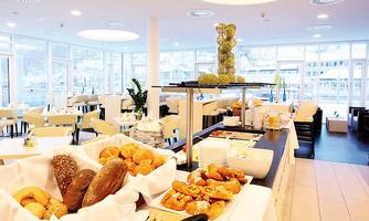 A modern restaurant with bright colors and plenty of daylight. Various rolls and baked goods are arranged on a table.