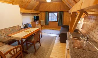 A cozy chalet with a wooden interior design. It features a dining area, a seating area, and a small kitchenette.