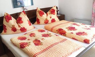 A cozy bedroom with two beds and colorful bedspreads. A picture and a piece of art hang on the wall.