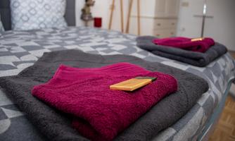 A cozy bedroom with a bed and neatly folded towels. Next to the towels lies a small notebook.