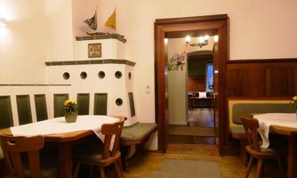 A cozy dining area with wooden chairs and tables. In the background, another room is visible, which also looks inviting.