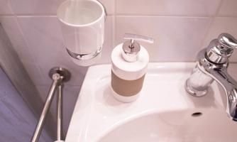 A modern bathroom with a soap dispenser and a toothbrush holder. The fixtures and tiles are elegant and clean.
