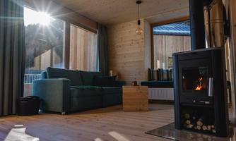 A cozy living room with a blue couch and a wooden fireplace. The sunlight streams through the window, creating a warm atmosphere.