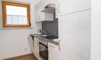 A modern kitchen with bright cabinets and a shiny stove. The window lets in plenty of daylight and creates an inviting atmosphere.