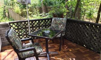 A quiet terrace with a table and two comfortable chairs. Surrounded by plants and trees, ideal for relaxing.