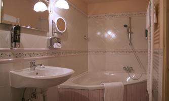 A modern bathroom with a bathtub and a sink. The walls are tiled in light colors and the lighting is soft.