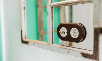 A mirror with a vintage wooden frame. It contains an outlet and a switch.
