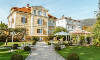 An elegant building with a beautiful garden landscape. Stylish furniture and trees complete the pleasant atmosphere.